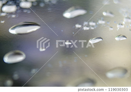 Side angle of clear raindrops on a transparent surface. Rain reflections theme. 119030303