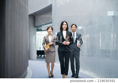 Male and female business team in suits walking in the office corridor 119030392