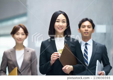 Male and female business team in suits walking in the office corridor 119030393
