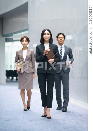 Male and female business team in suits walking in the office corridor Male and female business team in suits walking in the office corridor 119030394