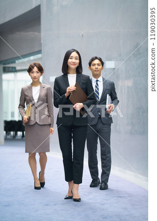 Male and female business team in suits walking in the office corridor 119030395