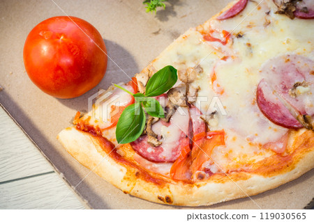cooked pizza with salami and sausage in a box on a wooden table cooked pizza with salami and sausage in a box on a wooden table 119030565