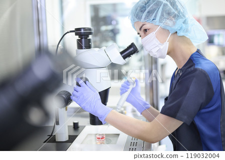 Embryologist using a microscope in the incubation lab 119032004