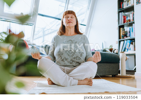 portrait of middle aged woman meditating, yoga at home portrait of middle aged woman meditating, yoga at home 119033504