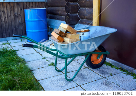 Wheelbarrow with Firewood and Tools in a Backyard Wheelbarrow with Firewood and Tools in a Backyard 119033701