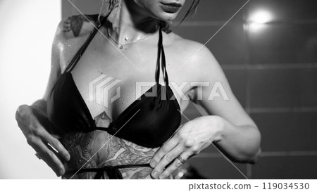 Sexy woman fashion model takes a shower in a swimsuit, posing for the camera. Monochrome photography. Sexy woman fashion model takes a shower in a swimsuit, posing for the camera. Monochrome photography. 119034530