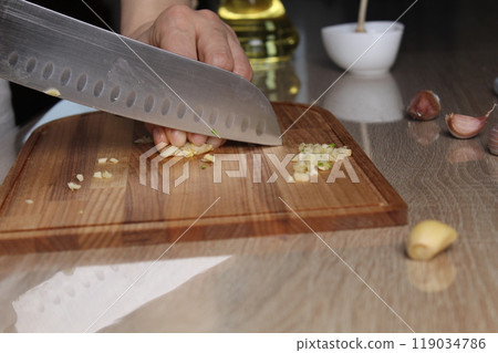 Small chopped garlic on a cutting board close-up of a black foreshortening. The Process of Slicing Garlic Seasoning 119034786