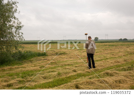 A male surveyor works with a GNSS receiver, from the back 119035372
