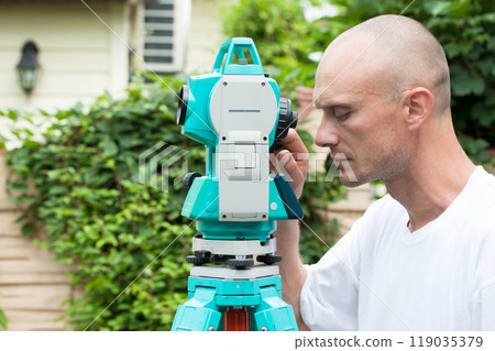 A surveyor works with a total station device A surveyor works with a total station device 119035379