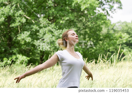 A woman rests in nature with her arms outstretched, the concept of emotional balance A woman rests in nature with her arms outstretched, the concept of emotional balance 119035453