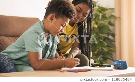 Young woman coloring with little brother in living room at home 119035494