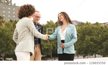 Happy adult businesswomen shaking hands in city Happy adult businesswomen shaking hands in city 119035550