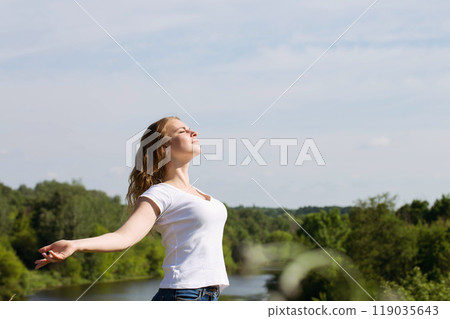 A beautiful woman rests in nature with her arms outstretched 119035643