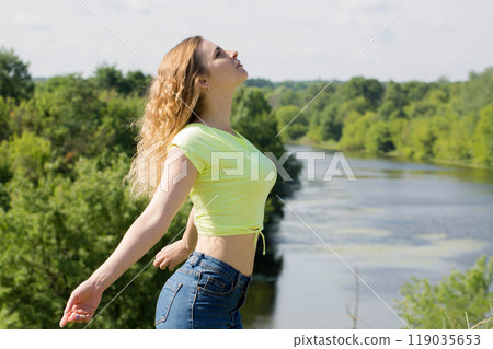 A woman rests in nature with her arms outstretched, the concept of emotional balance A woman rests in nature with her arms outstretched, the concept of emotional balance 119035653
