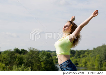 A beautiful woman rests in nature with her arms outstretched, the concept of emotional balance A beautiful woman rests in nature with her arms outstretched, the concept of emotional balance 119035654