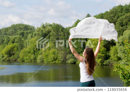 A young woman holds a white cloth, the concept of purity and freedom 119035656