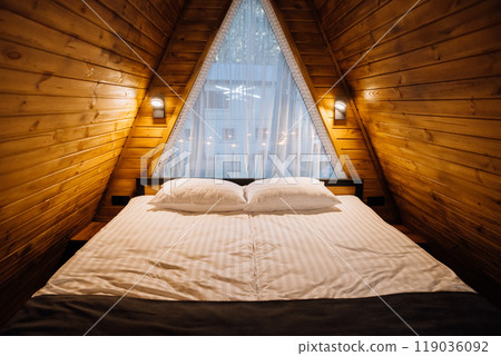Cozy wooden cabin bedroom with large bed and natural light, creating a warm and inviting atmosphere Cozy wooden cabin bedroom with large bed and natural light, creating a warm and inviting atmosphere 119036092