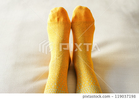 Close-up of a woman's legs wearing yellow woolen socks on a white background Close-up of a woman's legs wearing yellow woolen socks on a white background 119037198