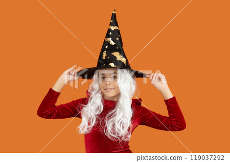 Trick or treat. All Hallows costume party celebration. All Hallows witch. Girl in Halloween witch costume. Happy Halloween. Girl witch in Halloween costume isolated on orange. Pointed brim Trick or treat. All Hallows costume party celebration. All Hallows witch. Girl in Halloween witch costume. Happy Halloween. Girl witch in Halloween costume isolated on orange. Pointed brim 119037292