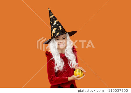 Halloween witch girl isolated on orange. Pumpkin on Halloween. Witch All Hallows costume of girl. October 31 pumpkin. Costume party. Halloween pumpkin in hand of witch girl. Seasonal decoration Halloween witch girl isolated on orange. Pumpkin on Halloween. Witch All Hallows costume of girl. October 31 pumpkin. Costume party. Halloween pumpkin in hand of witch girl. Seasonal decoration 119037300