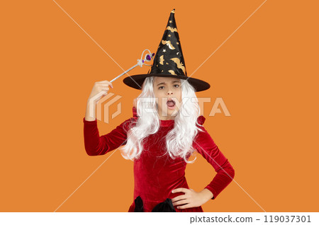 Halloween costume party. All Hallows witch girl. Girl in witch costume hold magic wand. Happy Halloween. Girl witch in Halloween costume isolated on orange. Trick or treat. Having fun Halloween costume party. All Hallows witch girl. Girl in witch costume hold magic wand. Happy Halloween. Girl witch in Halloween costume isolated on orange. Trick or treat. Having fun 119037301