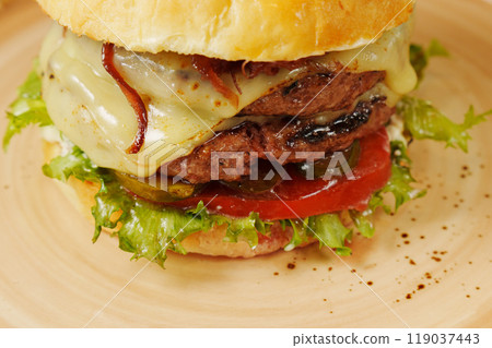 Juicy burger stacked with fresh ingredients showcases vibrant colors in a warm restaurant setting 119037443