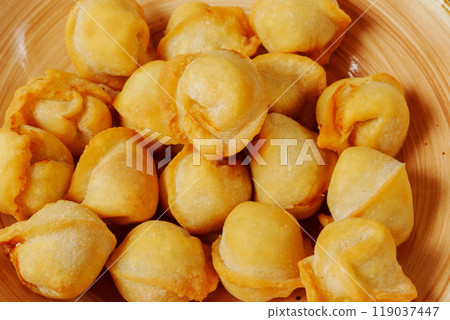 Golden dumplings arranged artfully in a wooden bowl, showcasing their crispy texture and inviting aroma on a sunny afternoon Golden dumplings arranged artfully in a wooden bowl, showcasing their crispy texture and inviting aroma on a sunny afternoon 119037447
