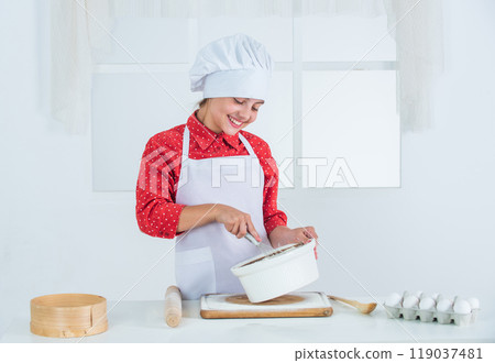 happy girl prepares dough in kitchen, culinary 119037481