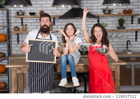 happy family in kitchen. copy space on board. family in kitchen making breakfast together. small girl have fun with mom and dad. mother father and child cooking. family bonding time. Free time happy family in kitchen. copy space on board. family in kitchen making breakfast together. small girl have fun with mom and dad. mother father and child cooking. family bonding time. Free time 119037522