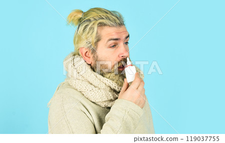Runny nose and other symptoms of cold. injecting drops in nose. coronavirus from china. Trying not sneeze. nursing nasal cold or allergy. man in scarf hold nasal spray. Cold flu remedies 119037755