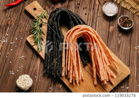 Variety of black and light meat sticks on board with herbs and spices, ideal for culinary display 119038278