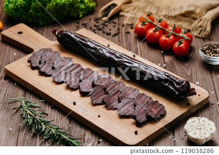 Smoked salami sticks on a wooden board with herbs, perfect for charcuterie boards and gourmet snacks Smoked salami sticks on a wooden board with herbs, perfect for charcuterie boards and gourmet snacks 119038286
