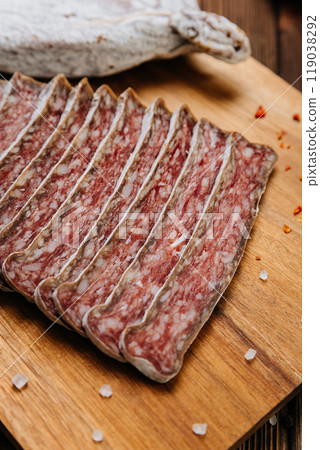 Dry-cured salami on board, ideal for rustic charcuterie presentations and gourmet food styling 119038292