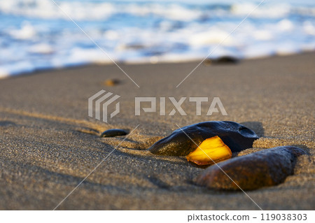 A beautiful piece of amber lies on the warm sand of the beach A beautiful piece of amber lies on the warm sand of the beach 119038303