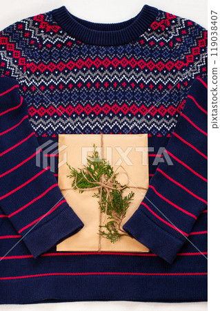 New year 2021 flatlay. Christmas blue and pink ornamental sweater, gift box in eco kraft paper,pine tree.Winter holidays New year 2021 flatlay. Christmas blue and pink ornamental sweater, gift box in eco kraft paper,pine tree.Winter holidays 119038407