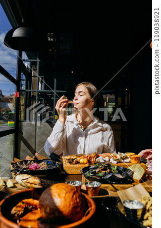 Woman enjoying seafood platter with oysters and shrimp in restaurant. Food lifestyle content 119038921