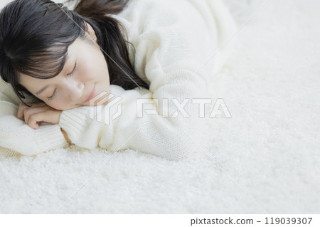 A woman lying down in a white knitted sweater 119039307