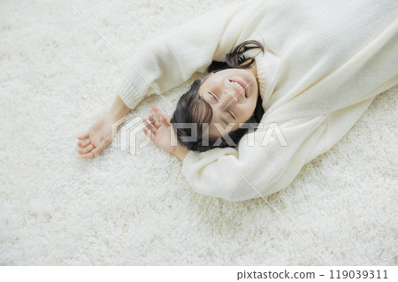 A woman lying down in a white knitted sweater 119039311