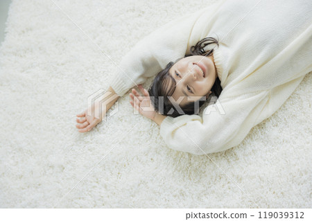 A woman lying down in a white knitted sweater A woman lying down in a white knitted sweater 119039312