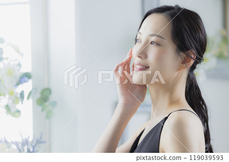 A woman in a black camisole dress standing by the window A woman in a black camisole dress standing by the window 119039593