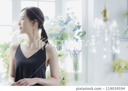 A woman in a black camisole dress standing by the window 119039594