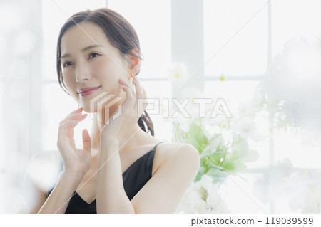 A woman in a black camisole dress standing by the window 119039599