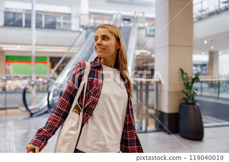 A young woman is exploring a modern and vibrant shopping mall filled with exciting shops 119040019