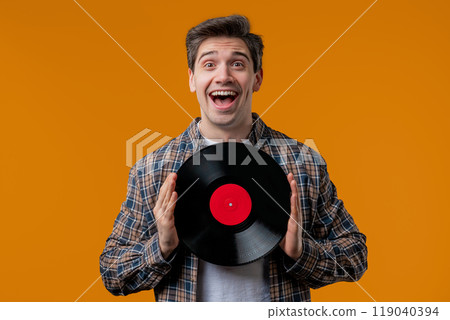 Stylish mature man with vinyl record disc on yellow. Hobby, music, collection 119040394