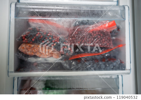 Lingonberries, blueberries, sea buckthorn, cranberries frozen for winter in bags. Freezer with food  119040532