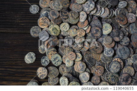Pile of bronze Roman coins on old dark wooden table, top view of Ancient money, vintage background. Concept of antique, Empire, texture, civilization 119040655