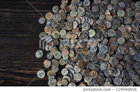 Lot of Ancient Roman coins on old dark wooden table, top view of pile of bronze money, vintage background. Concept of antique, texture, civilization and histor 119040656