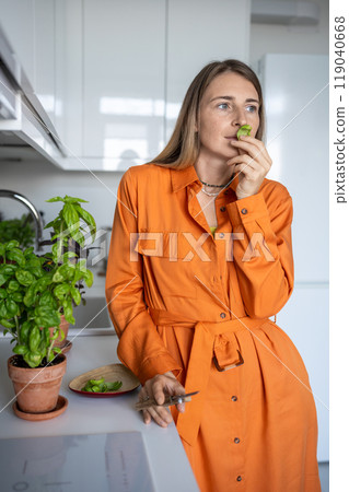 Woman sniffs home-grown basil leaf. Female gardener enjoying smell of green basil plant Woman sniffs home-grown basil leaf. Female gardener enjoying smell of green basil plant 119040668