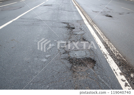 Broken asphalt road in city and untimely repair. Pothole asphalt road. Roadway in bad condition 119040740