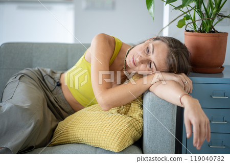 Tired dreaming woman leaning on armrest of sofa resting at home. Thoughtful female relaxing on couch 119040782